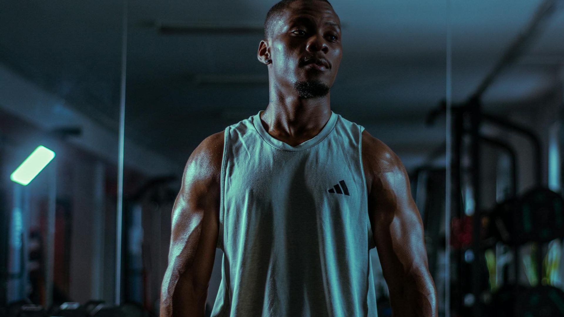 Professional male athlete focused on functional strength training in a dark gym.